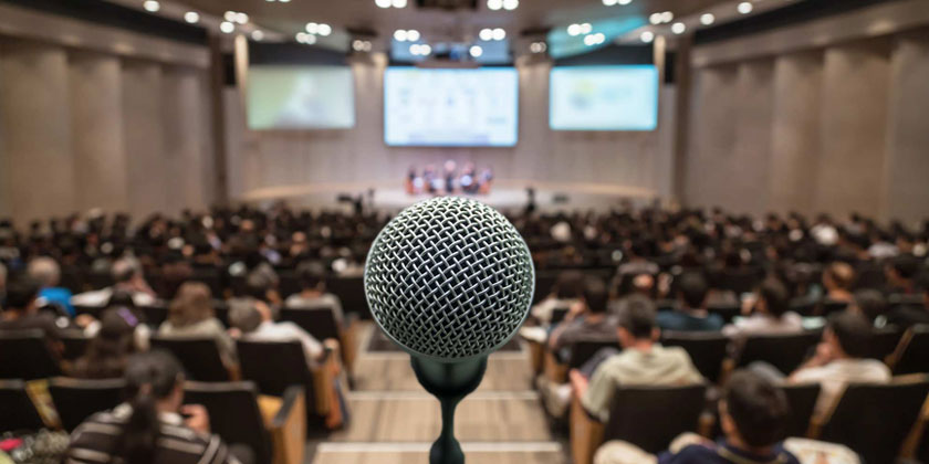 Gros plan sur un micro avec en arrière plan, la salle vide ou prendra place l'auditoire