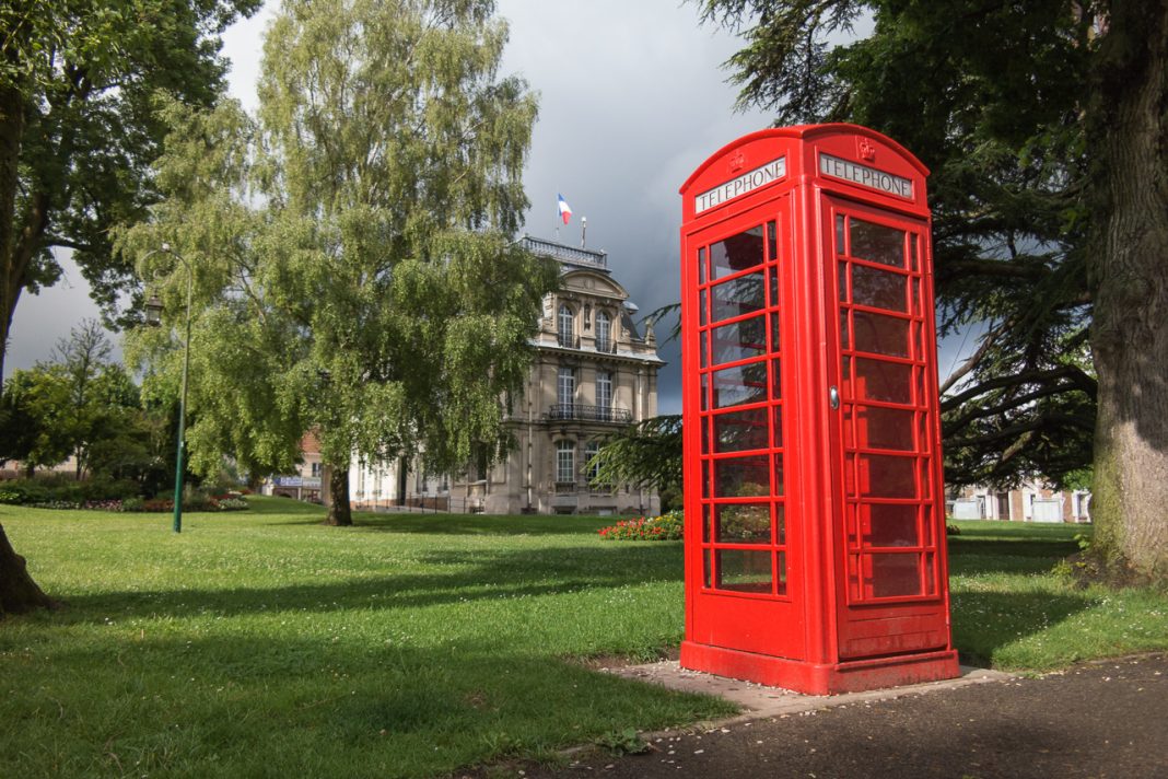 cabine téléphonique anglaise sur la pelouse d'un parc bordant un bâtiment scolaire ou administratif